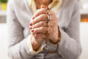 Symbolbild: Gläubige Seniorin mit Kreuz in den Händen zu Christi Himmelfahrt