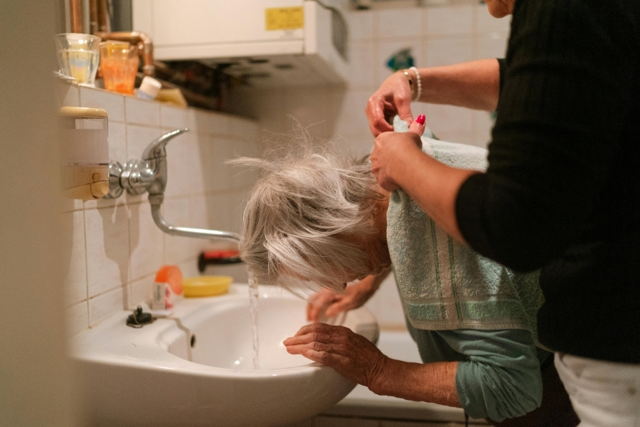 Pflegekraft hilft Seniorin beim Waschen