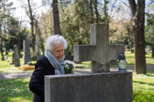 Seniorin an einem Grabstein