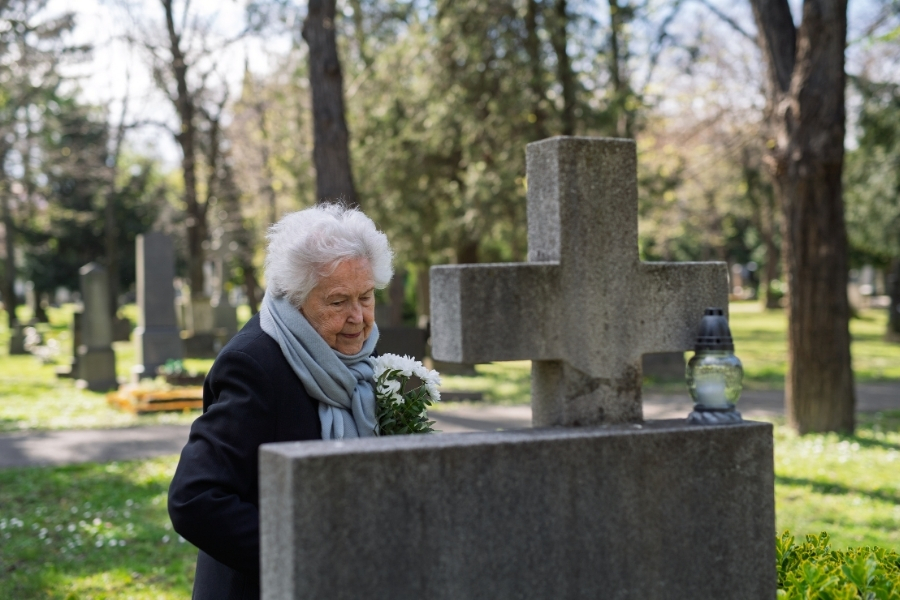 Seniorin an einem Grabstein