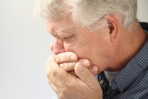 Senior hält sich die Hände vor den Mund