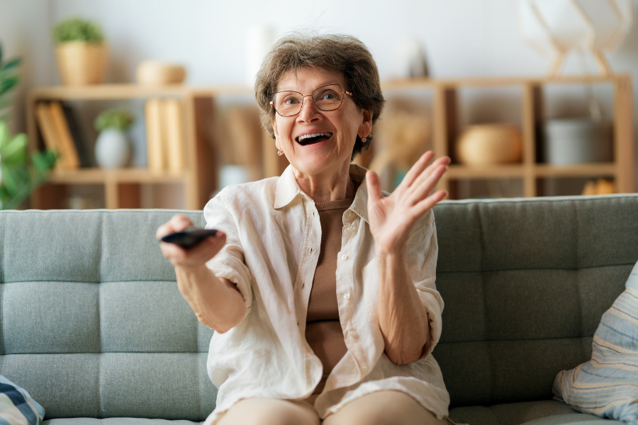 Szczęśliwa seniorka oglądająca telewizję